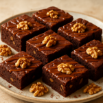 Καρύδινο brownie σοκολάτας σε κομμάτια με γυαλιστερή καραμέλα από πάνω, σε πιάτο σερβιρίσματος